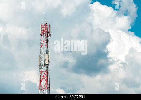 Mobile telephony base station on communication tower against cloudy summer sky Stock Photo