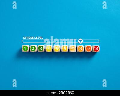 Indicator measuring stress level. High level of stress. Stress level numbers on wooden cubes with a stress meter on blue background. Stock Photo