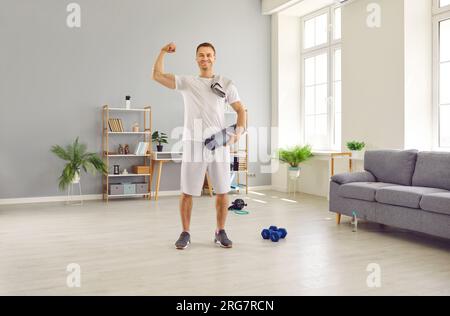 Handsome middle aged strong man showing biceps holding fitness mat Stock Photo