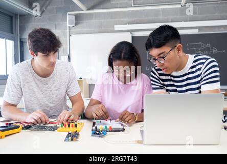 Group of teenage multiethnic students work as a team in technology class with computer and electronic systems Stock Photo