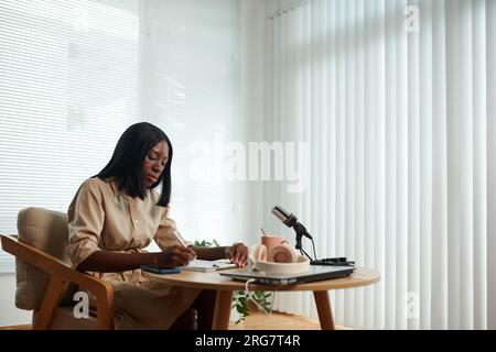 Serious Black young woman working on script for her podcast Stock Photo