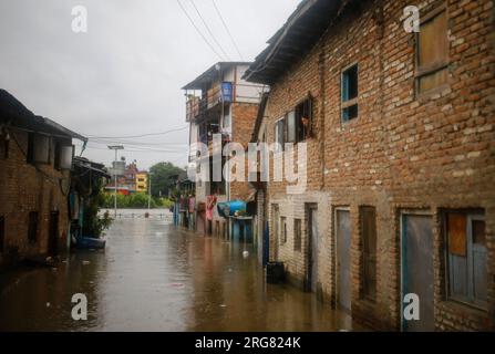 Kathmandu, Nepal. 08th Aug, 2023. A man takes his child outside their ...