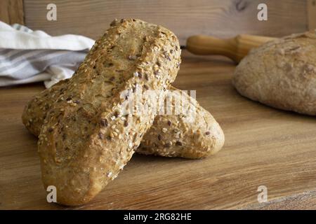 Close up of delicious and fresh cereals bread stick in the foreground and various breads in the background on the wooden table. Sesame seeds covered t Stock Photo