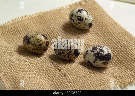Geometric composition of four quail eggs on sackcloth as background. Horizontal view. Stock Photo