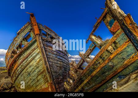 Old wooden fishing boats wrecked at the side of the sea, Isle of Mull Stock Photo