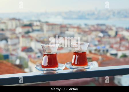 Two Turkish glasses in form of a tulip filled with hot black tea with view to the roofs of Uskudar district on Asian side of Istanbul, Turkey Stock Photo