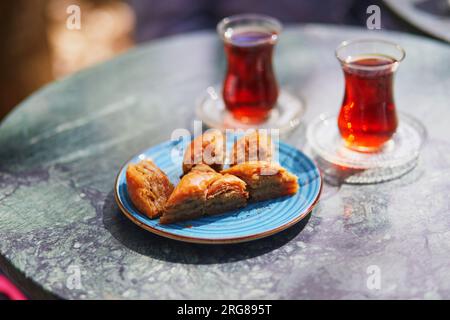 Traditional Turkish tea served in tulip shaped glasses with baklava sweets in cafe or restaurant in Istanbul, Turkey Stock Photo