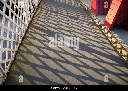 Latticed patterned balustrade with sunlight producing a shadow pattern on the pavement. Stock Photo