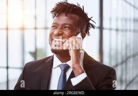 Cheerful and smiling businessman in a suit talking on the phone in the office Stock Photo