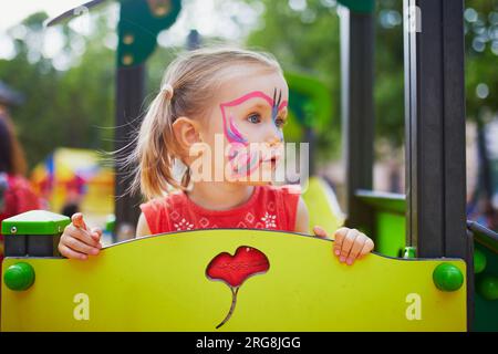 beautiful little girl with a painted fox on her face. face painting Stock  Photo