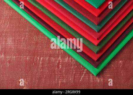 Stack of red and green fabrics on brown background, space for text Stock Photo