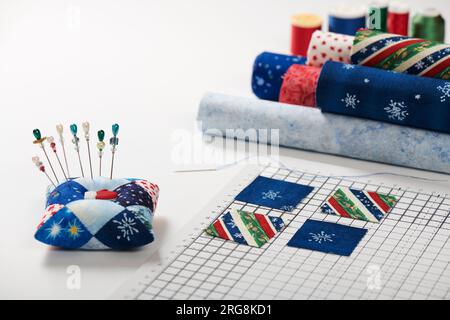 Preparing of square pieces of fabrics for sewing quilt on craft mat, pincushion, fabric rolls, spools of thread Stock Photo