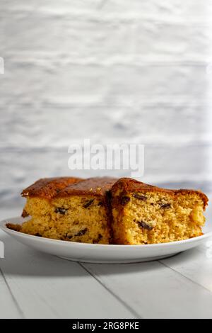 An English cake in a baking dish on a wooden board and a white wooden  table. Selective focus Stock Photo - Alamy