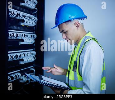Man, engineering and tablet for data center maintenance, server room programming or inspection in IT cybersecurity. Electrician or person on typing on Stock Photo