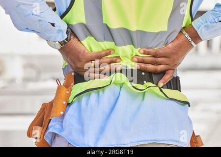 Man, architect and hands in back pain, accident or posture after construction injury on site. Rear view of male person, contractor or engineer with Stock Photo