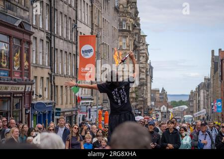 A fire eating street performer surrounded by crowds performs on the Royal Mile in Edinburgh during the Fringe festival, August 2023. Scotland, UK. Stock Photo