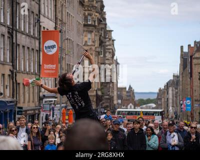 A fire eating street performer surrounded by crowds performs on the Royal Mile in Edinburgh during the Fringe festival, August 2023. Scotland, UK. Stock Photo