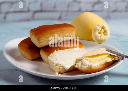 Some dinner rolls in Brazil are called "Bisnaguinha" filled with cheese and cream cheese on a white plate. Stock Photo