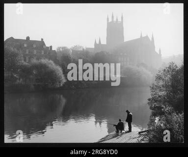 Angling in the River Severn on a misty morning, while the sun rises behind Worcester Cathedral in the distance. Stock Photo