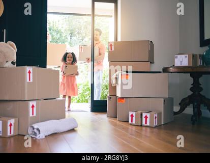 Gay couple, child and adoption moving in new home with boxes for property, investment or house together. Men walking with adopted girl in renovation Stock Photo