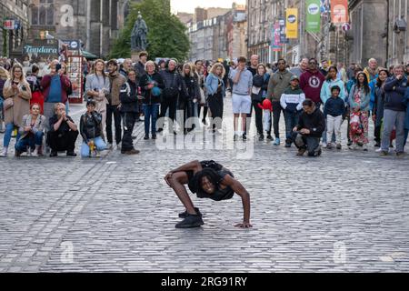 A member of Guinea act 'Afrique En Cirque' performs a contortion act on the Royal Mile in Edinburgh during the Fringe Festival, August 2023. Scotland. Stock Photo