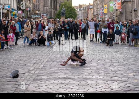 A member of Guinea act 'Afrique En Cirque' performs a contortion act on the Royal Mile in Edinburgh during the Fringe Festival, August 2023. Scotland. Stock Photo