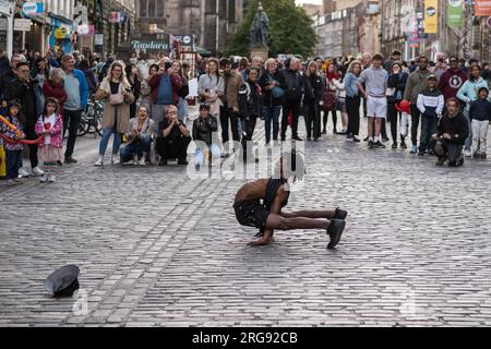 A member of Guinea act 'Afrique En Cirque' performs a contortion act on the Royal Mile in Edinburgh during the Fringe Festival, August 2023. Scotland. Stock Photo