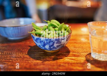 Green soy beans (edamame) in ceramic bowl on table in Japanese restaraunt Stock Photo