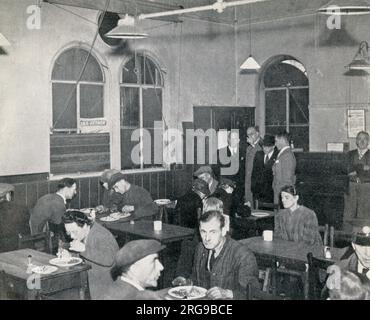 Scene inside the first British Restaurant at Woolmore Street, Poplar, east London, one of a number of communal restaurants during the Second World War providing a cooked meal, with dessert and a cup of tea, for around the cost of 1s.2d. While operated on a canteen basis, meals were eaten at a table and allowed people, including war workers and those who had bombed out of their homes or might have difficulty cooking or making a packed lunch at home, a nutritious and affordable meal, which could be eaten in addition to wartime rations. Stock Photo