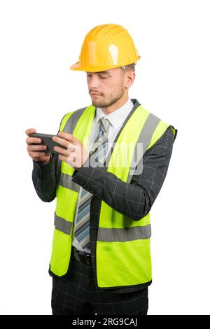 Portrait of a business man in a suit, with a hi-vis vest & hardhat reading a message on a mobile phone Stock Photo