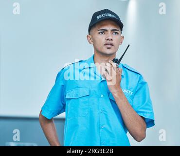 Security guard, walkie talkie and man in office in surveillance, communication or conversation. Safety, protection and serious bodyguard on radio to Stock Photo