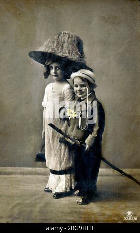 'Ethel' and her younger brother in fine fancy dress costume - this scene is in part a satire on the penchant for women to wear large and enveloping hats during this period. Stock Photo