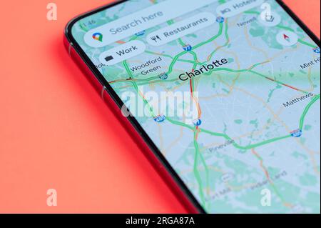 New York, USA - July 21, 2023: Car traffic on Charlotte google maps on smartphone screen close up view with red background Stock Photo