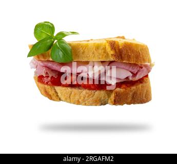 Ham and tomato sandwich between two slices of durum wheat semolina bread with basil leaves, isolated on white with clipping path included Stock Photo