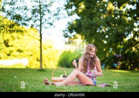 Girl blowing bubbles in park Stock Photo