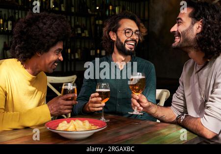Cheerful group of male friends gathering in a bar drinking beer and speaking Stock Photo