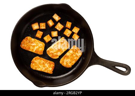 Fried slices and cubes of halloumi cheese with red chilli on cast iron frying pan isolated on white. Top view. Stock Photo