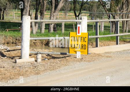 A yellow Traffic Hazard Road sign on an unsealed country road Stock Photo