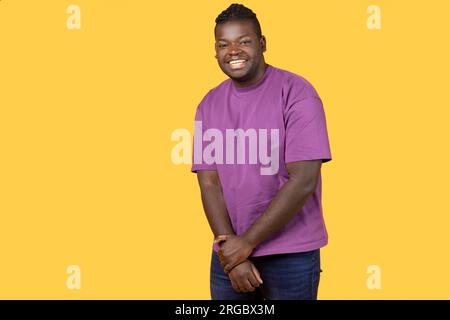 Shy African man looking at camera with toothy smile, studio Stock Photo