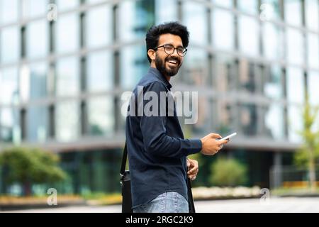 Happy middle eastern IT professional going to office, using phone Stock Photo