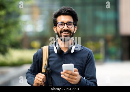 Portrait of positive hindu entrepreneur using phone outdoor Stock Photo