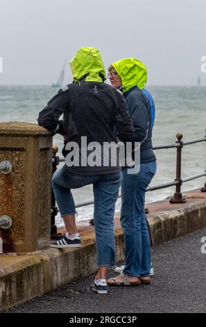 two people wearing sailing clothing in the poring rain on a wet day at cowes week on the isle of wight uk Stock Photo
