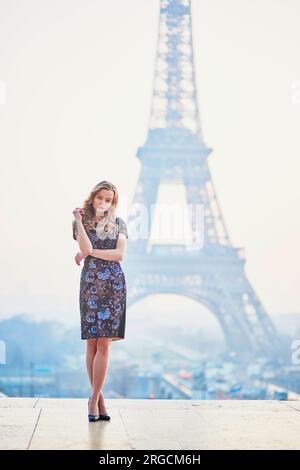 Beautiful elegant Parisian woman near the Eiffel tower at early morning Stock Photo
