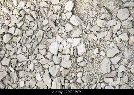 Road grave texture for background. White crushed stone. Top view of dirt road fragment. Dry land with stones. Stones and pebbles on the ground. Stock Photo