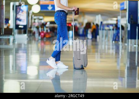 Closeup of woman legs with luggage in international airport. Tourism and travel concept Stock Photo