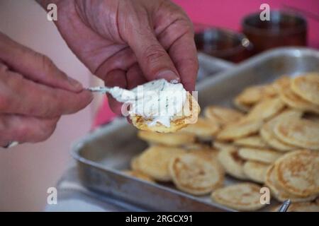 man spreading cream cheese onto a Bellini Stock Photo