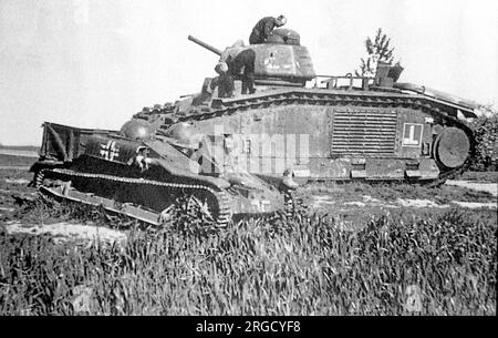 Captured Char B1 heavy tank and Renault UE Chenillette light tracked armoured carrier / prime mover, abandoned by German forces and being inspected by French civilians. Stock Photo