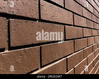 Closeup view of a fashionable deep rich brown brick wall. Point of view features vanishing point perspective. Stock Photo