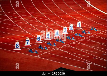 Start of sprint race. Numbers and starting blocks on the red track. Athletics stadium. Track and field photo. Starting numbers on athletics track. Stock Photo