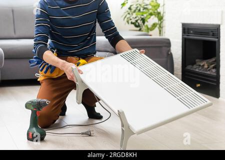 the master repairs the electric heater Stock Photo